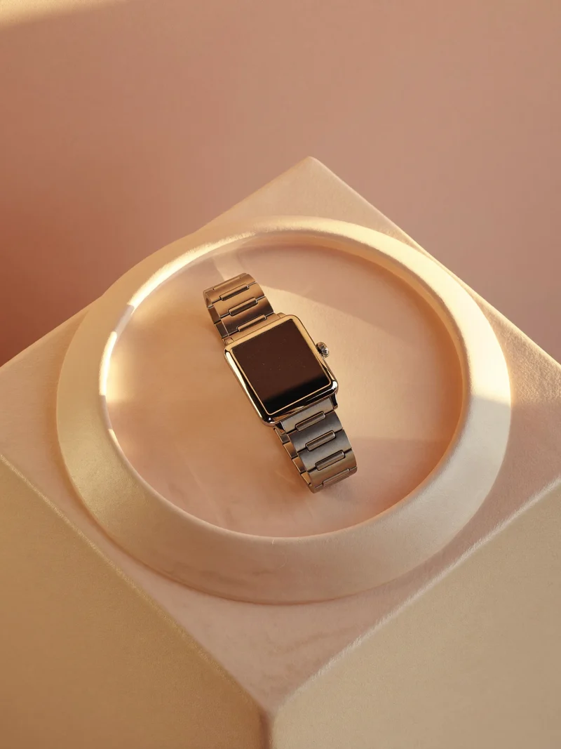 Smartwatch med tom mørk skive på et pastelfarvet stativ set oppefra